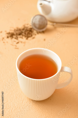 Cup of tasty hojicha green tea on beige background