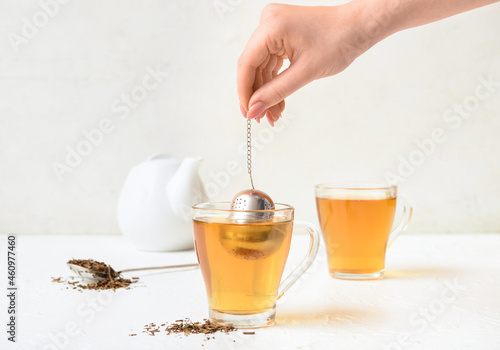 Woman preparing tasty hojicha green tea on white background