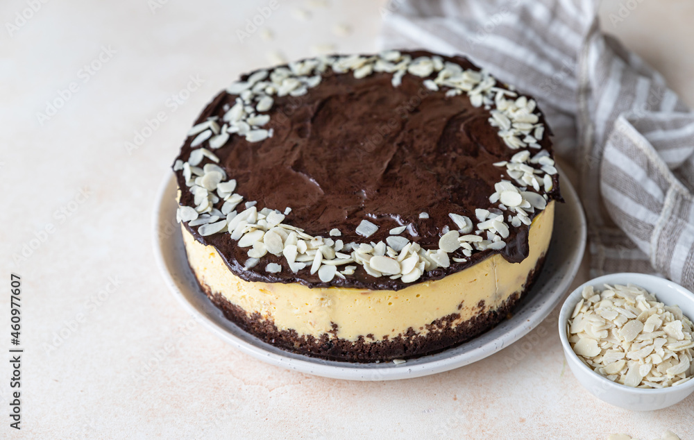 Delicious creamy cheesecake decorated with chocolate glaze and almond, light concrete background. No bake mousse dessert.