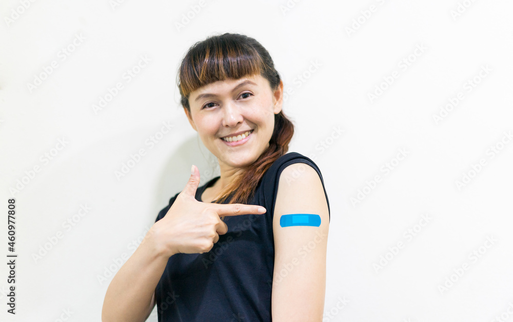 Asian woman smiling using adhesive bandage blue at arm after injection vaccinated on white isolate background. Covid 19 vaccine disease preparing. Asian woman smiling using adhesive bandage blue at arm after injection vaccinated on white isolate background. Covid 19 vaccine disease preparing.