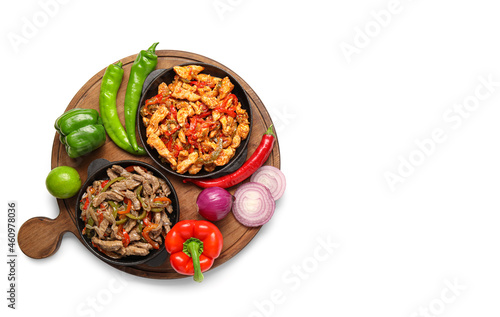 Frying pans with delicious Fajita and vegetables on white background