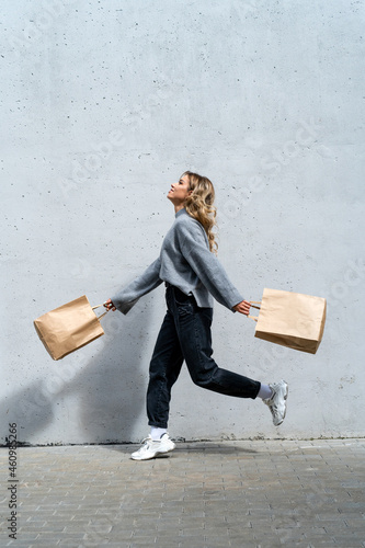 Happy woman walking along street with two shopping bags