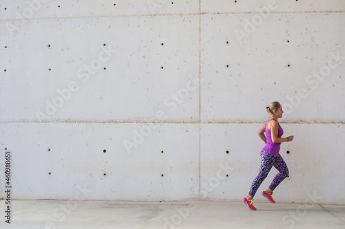 Sporty Woman. Beautiful Woman Running In The City Next To Buildings With Modern Architecture . Fitness, Workout, Sport, Lifestyle Concept.