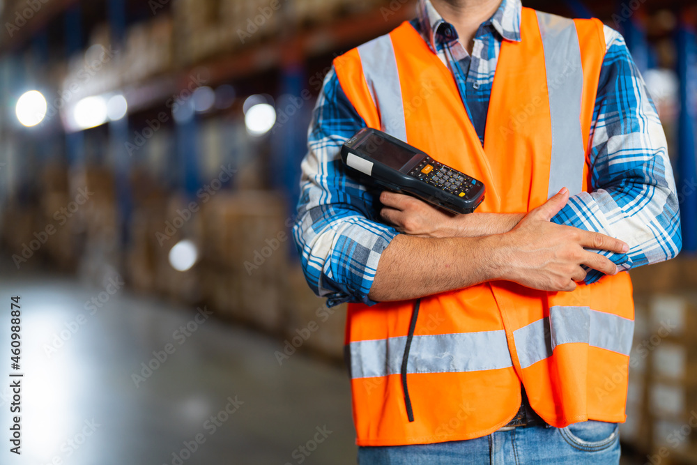 Closeup warehouse worker standing in large warehouse distribution center holding barcode reader. Closeup warehouse worker standing in large warehouse distribution center holding barcode reader.