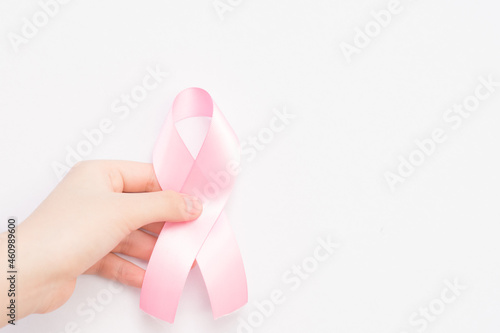 hand holding pink ribbon on breast cancer awareness day.