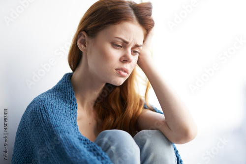 woman sitting on the windowsill with a blue plaid dreamy look