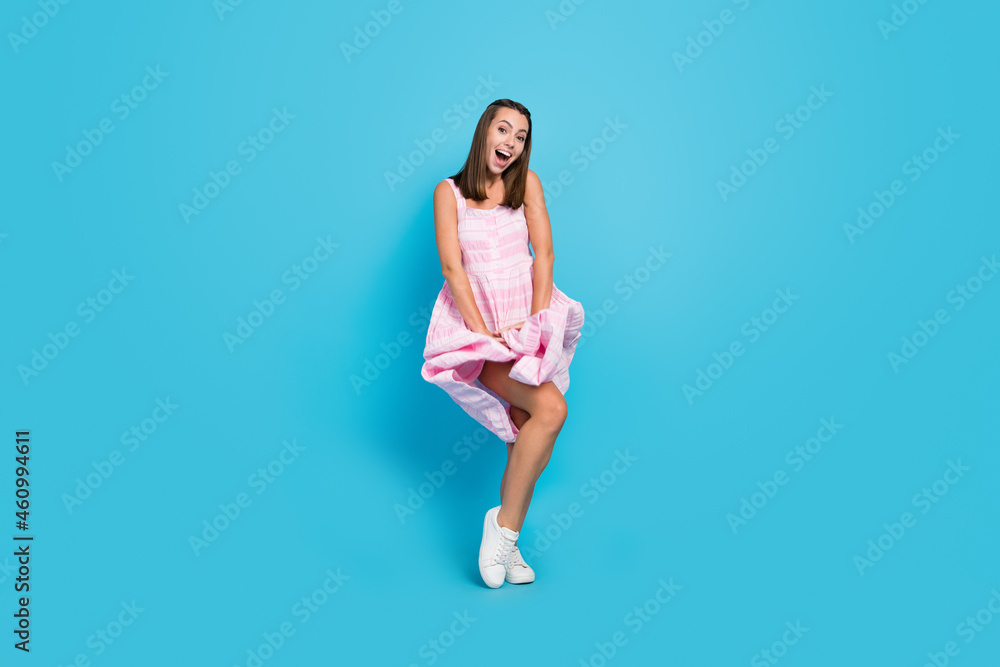 Full body photo of happy amazed young woman fly skirt blow wind summer isolated on blue color background Full body photo of happy amazed young woman fly skirt blow wind summer isolated on blue color background