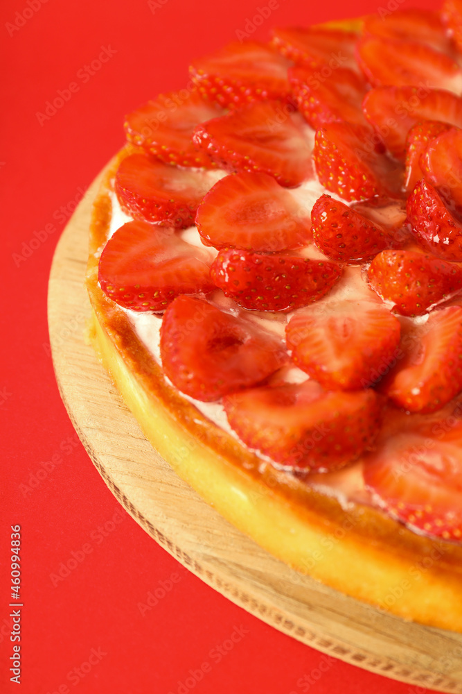Round board with strawberry tart on red background Round board with strawberry tart on red background