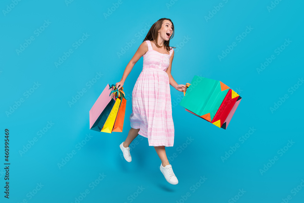 Full size photo of brunette haired stylish attractive beautiful amazed lady jump sale bags crazy isolated on blue color background Full size photo of brunette haired stylish attractive beautiful amazed lady jump sale bags crazy isolated on blue color background