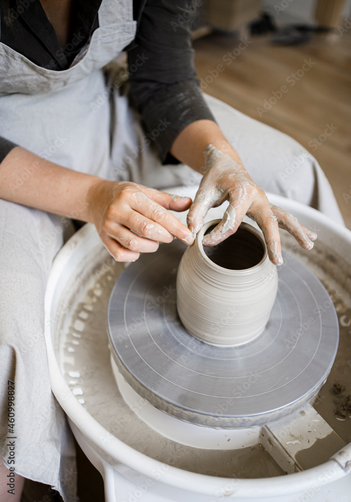 Female potter molding shape on pottery wheel in workshop Female potter molding shape on pottery wheel in workshop