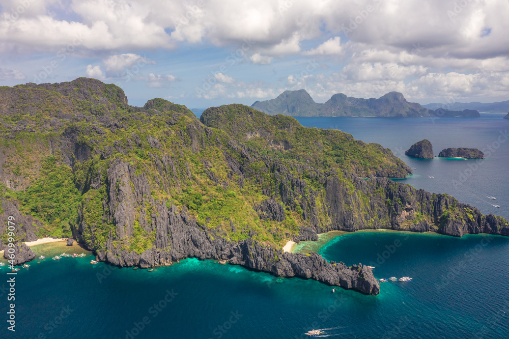 Aerial drone view of boats over a tropical coral reef and remote sandy Hidden Beach, El Nido, Palawan, Philippines.