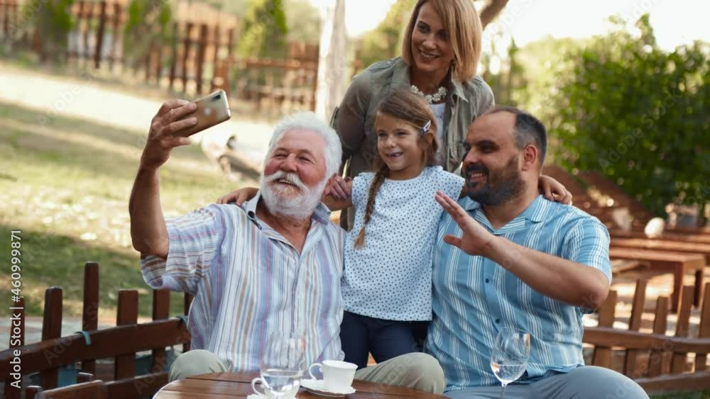Cheerful family using phone for selfie at the backyard. Senior man making photo of his beautiful happy family Cheerful family using phone for selfie at the backyard. Senior man making photo of his beautiful happy family