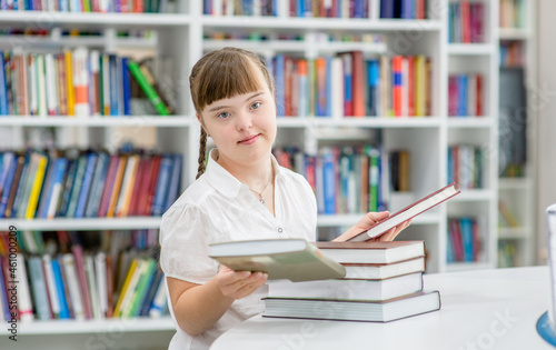 Portrait of a young girl with Downs syndrome at library. Education for disabled children concept