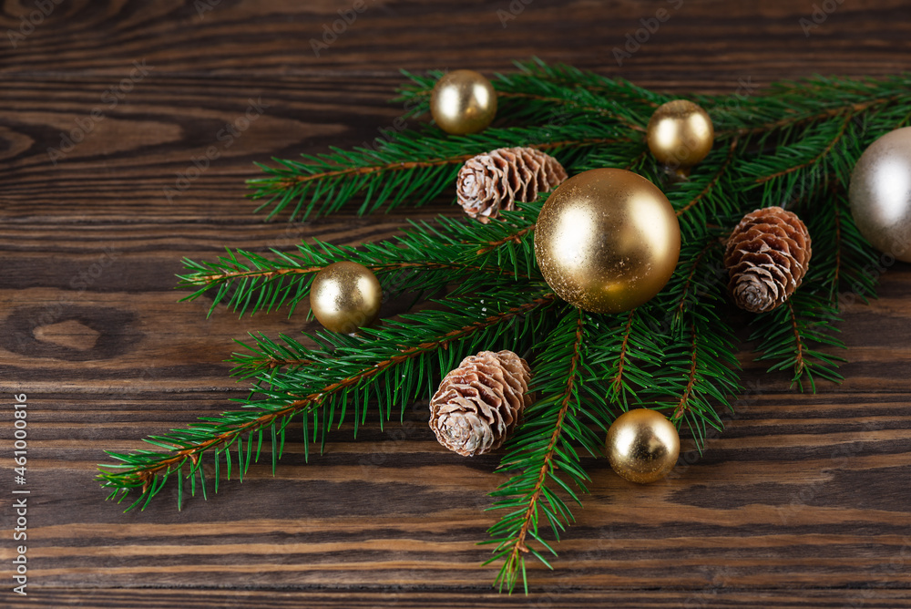 Fir branches with gold Christmas balls and cones on a brown wooden background. Christmas and New Year concept.