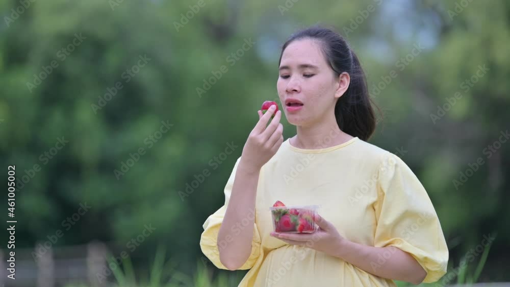 Pregnant woman eating strawberry resting outdoor Pregnant woman eating strawberry resting outdoor