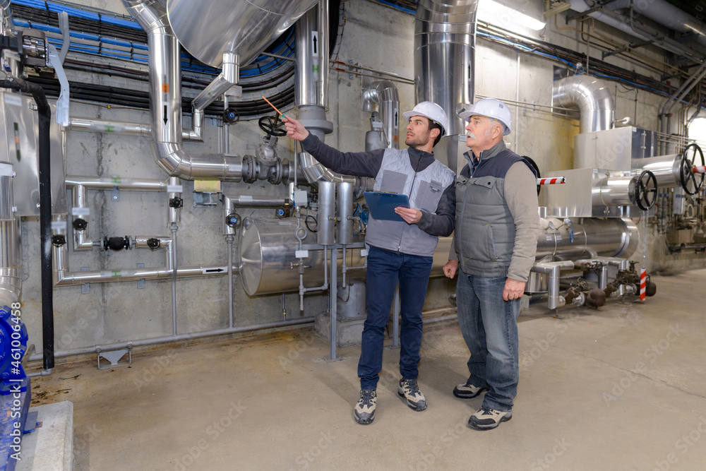 Fototapeta premium men looking at steel equipment in factory