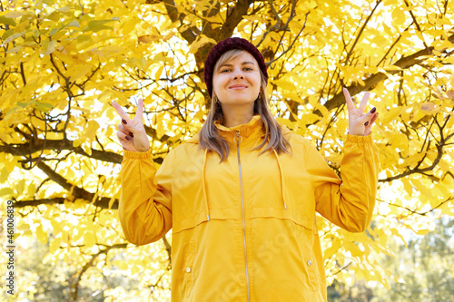 a woman smiles in front of an autumn yellow tree. autumn mood