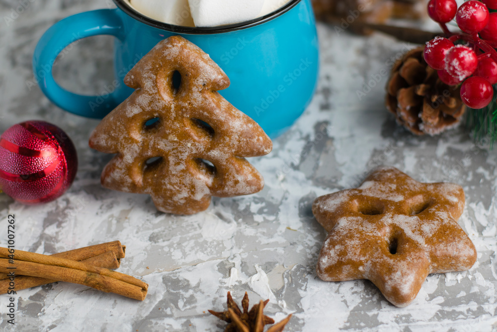 Fototapeta premium Christmas decor, delicious gingerbread cookies, marshmallows in a blue cup, star anise and cinnamon sticks on a light background. New Years celebration concept.