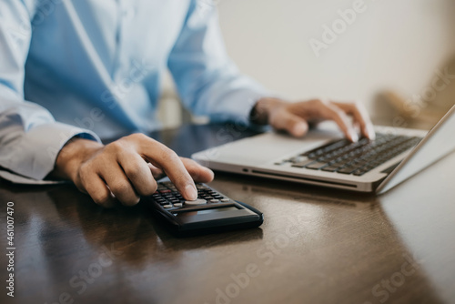 Businessman calculates financials with laptop on the table on the cost of home office in the evening.