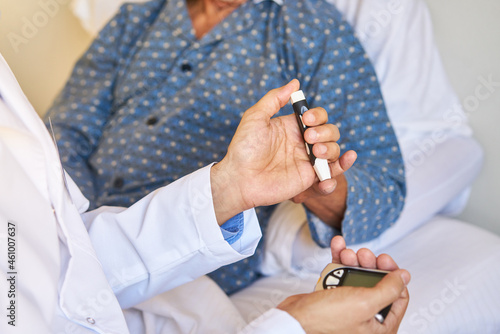 Doctor measures blood sugar on finger of senior patient