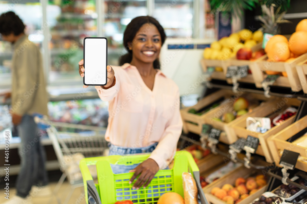 Black Woman Advertising Grocery Shopping Application Showing Phone In Supermarket - obrazy, fototapety, plakaty 