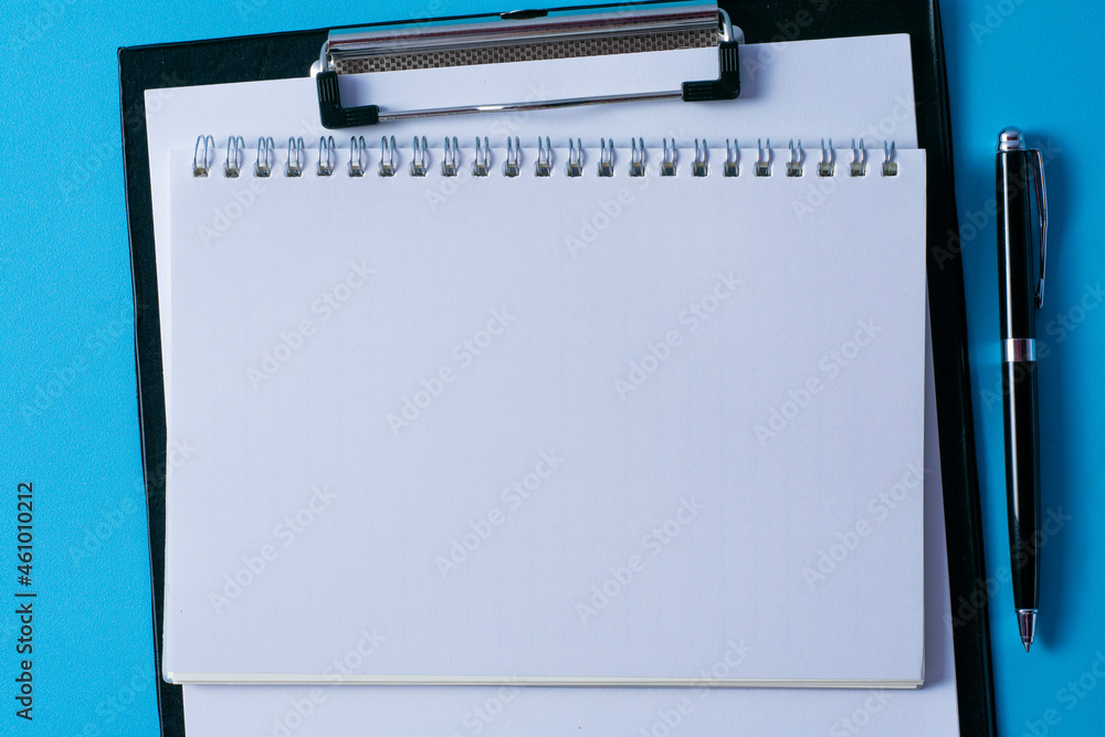 Top view of blank paper on clipboard on blue background and different objects. Minimal flat lay style. Top view of blank paper on clipboard on blue background and different objects. Minimal flat lay style.