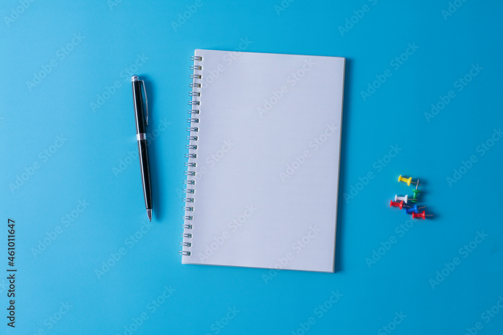 Top view of blank open notebook on blue background and different objects. Minimal flat lay style. Top view of blank open notebook on blue background and different objects. Minimal flat lay style.