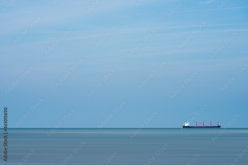 Container ship sailing at sea with a blue sky as background Container ship sailing at sea with a blue sky as background