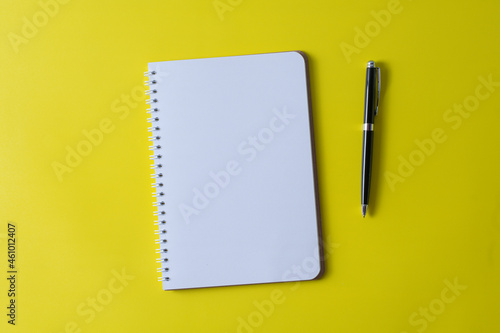 Top view of blank open notebook on yellow background and different objects. Minimal flat lay style.