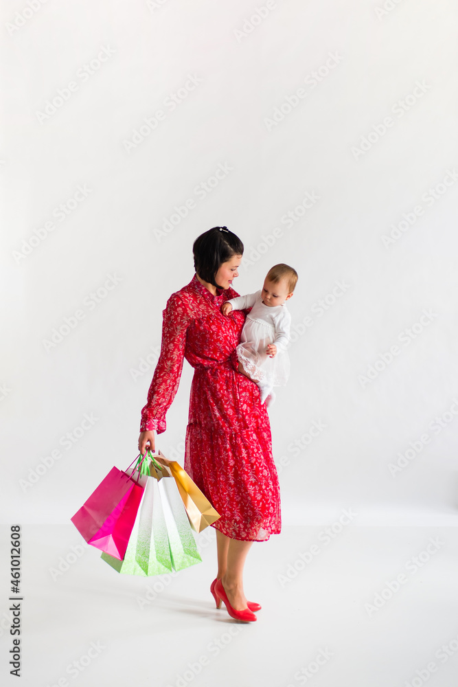 Black Friday. Woman is holding packages. Mom and little child are shopping. White background. Black Friday. Woman is holding packages. Mom and little child are shopping. White background.