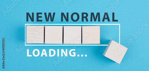 The words new normal are standing on wooden cubes, loading bar, blue colored background photo