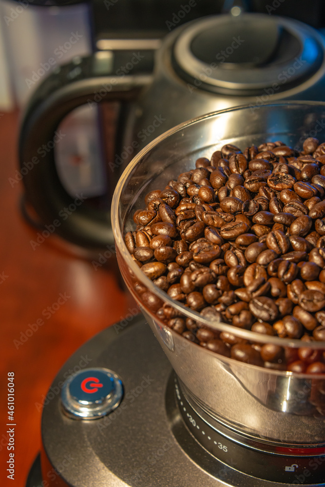 Fototapeta premium Coffee grinder with red start button, filled with fresh coffee beans, closeup, details