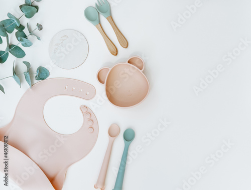 Baby feeding accessories. Silicone bib, Baby set dishes. Flat lay, top view, copy space.