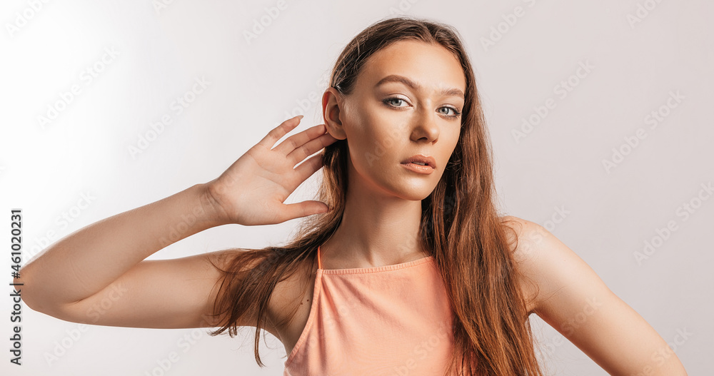 Beautiful young girl holds his hand near his ear, wants to hear better on a white background with a place for advertising mockup Beautiful young girl holds his hand near his ear, wants to hear better on a white background with a place for advertising mockup