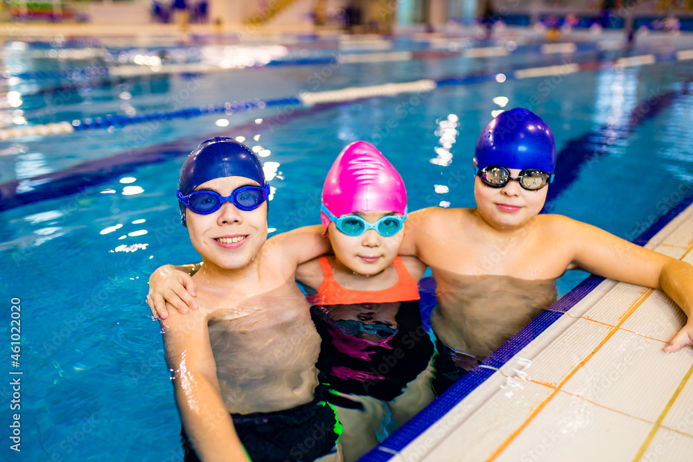 Disabled boys and girl with Down syndrome in swimming cap with goggles