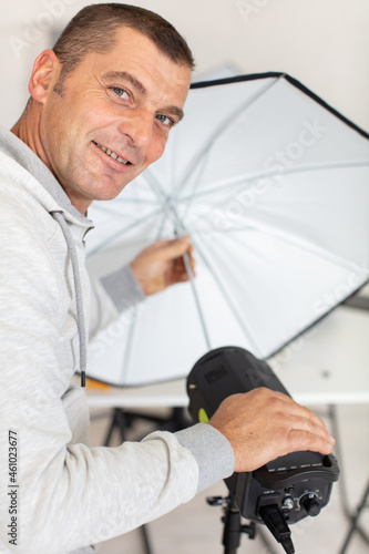 cheerful photographer setting light in photo studio photo