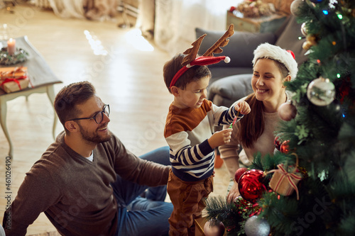 Happy family enjoys in decorating Christmas tree in the living room.