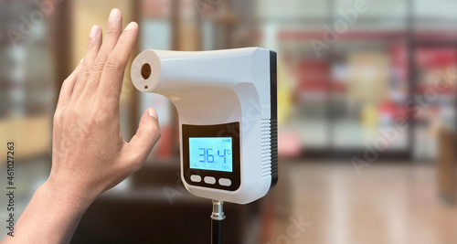 Hand customer of the front door with Digital thermometer temperature scanning machine before entering the store.