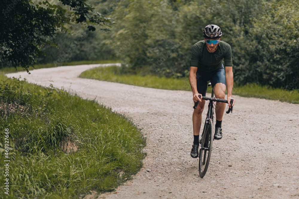 Fototapeta premium Male athlete in sport outfit cycling on forest trail