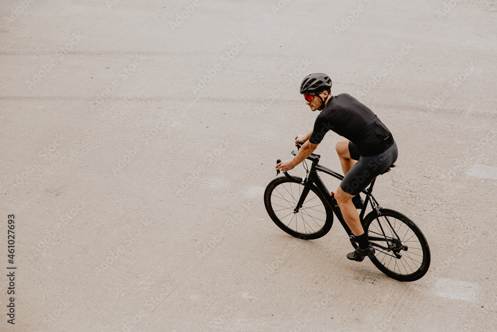Obraz premium Active man in sport outfit riding black bike outdoors