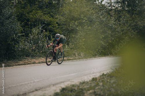 Muscular sportsman riding bike on high speed among forest © Tymoshchuk