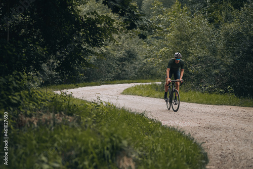 Muscular man in sport clothes riding bike on trail