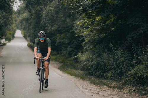 Sporty man in helmet and glasses riding bike on road © Tymoshchuk