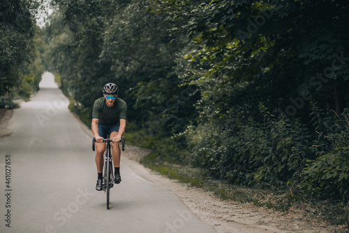 Fototapeta Naklejka Na Ścianę i Meble -  Cyclist in helmet and glasses riding bike among green nature