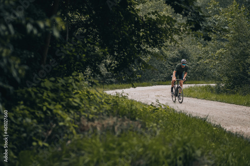 Sporty man in helmet and glasses riding bike on nature © Tymoshchuk