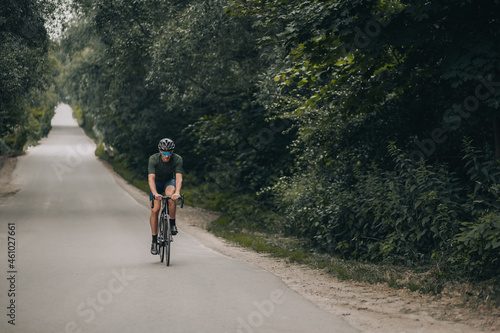 Strong cyclist using black bike for training outdoors