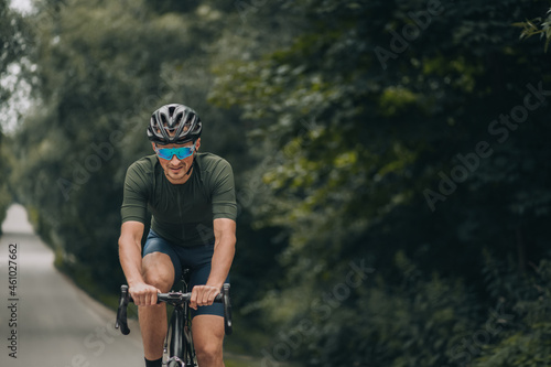Fototapeta Naklejka Na Ścianę i Meble -  Healthy and fit man riding bike on road among green nature