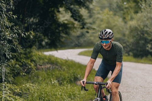 Happy man riding black bike among green forest