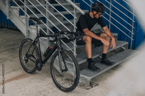 Man resting on metal stairs after active cycling