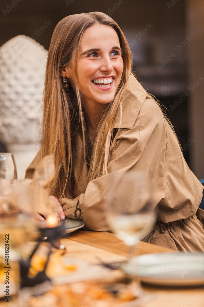 Blond cheerful stylish woman enjoying with friends during dinner. Beautiful smiling young woman conversating with friends. Blond cheerful stylish woman enjoying with friends during dinner. Beautiful smiling young woman conversating with friends.